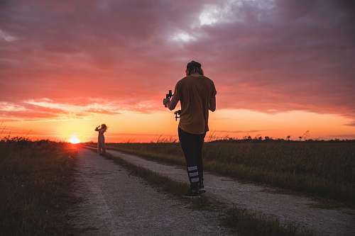 person man taking photo of woman during golden hour outdoors