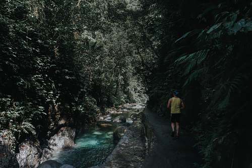 person man walking beside river near mountain during daytime nature