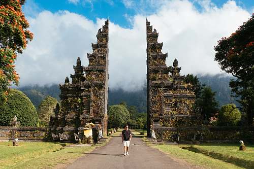 person man walking between building under white clouds temple