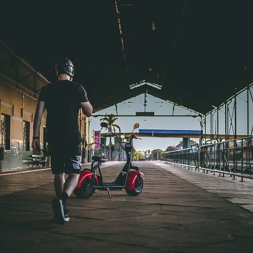 person man walking near red motor scooter bicycle