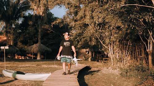 person man walking on dock holding rod during daytime people