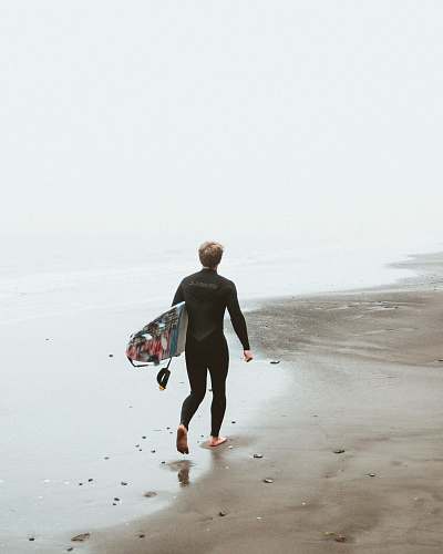 people man walking on the beach carrying surfboard person