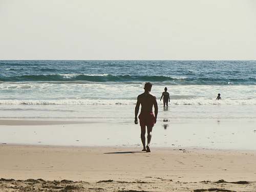person man walking towards shore during daytime people