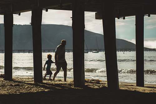 person man walking with boy on shore apparel