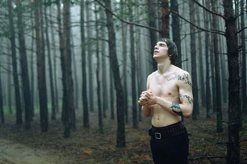 people man wearing black bottoms standing surrounded by tall trees during daytime person