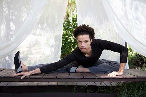 person man wearing black long-sleeved Henley shirt stretching on wooden table fitness
