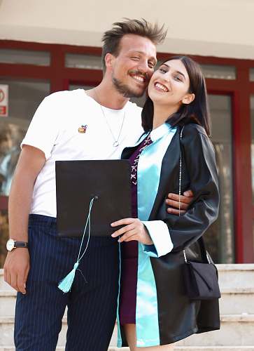 person man wearing white crew-neck shirt besides woman wearing black graduation gown apparel