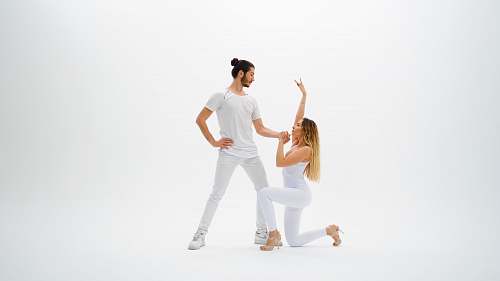 person man wearing white shirt holding hands with woman wearing white pants dance pose