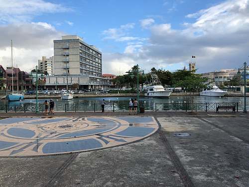 person people standing near lake viewing city with high-rise buildings under blue and white skies boat