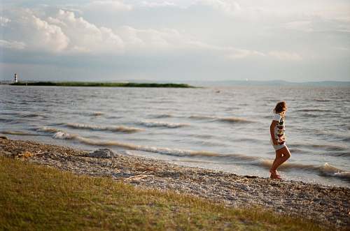 person person walking on seashore during daytime shoreline