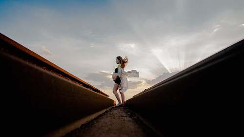 apparel pregnant woman standing near rail while holding tummy clothing