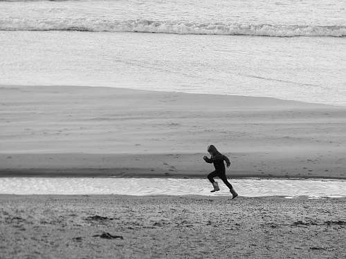 person running person on seashore during daytime black-and-white