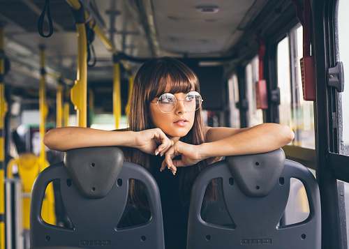 person selective focus photography of woman wearing eyeglases riding bus face