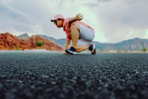 asphalt shallow focus photo of man wearing pink curved brim cap tarmac