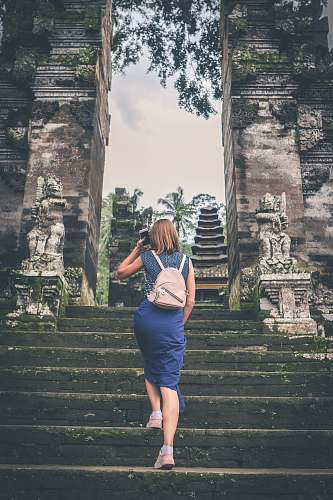 person shallow focus photography of woman in blue dress walking towards temple people