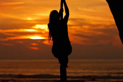 person silhouette photo of a man holding rope on seashore during sunset people