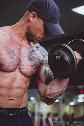 person topless man holding black dumbell on right hand people