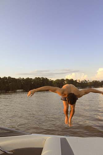 person topless man jumping during daytime water