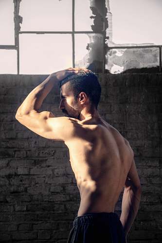 person topless man placing his right hand on his head arm