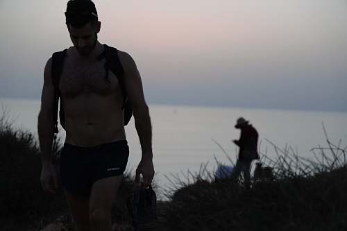 person topless man walking shorts