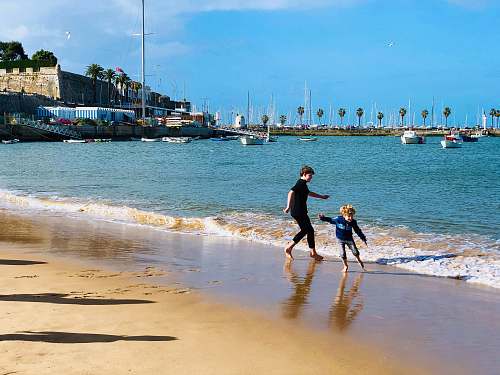 person two kids playing on seashore during daytime apparel