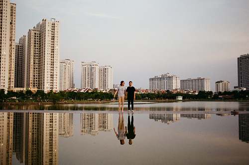 person two person standing beside body of water near buildings during daytime hanoi