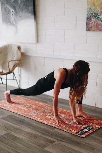 person woman bend down on orange floral mat inside room working out