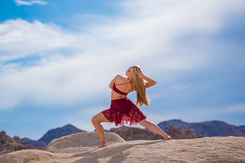 person woman dancing near mountain under white clouds during daytime people