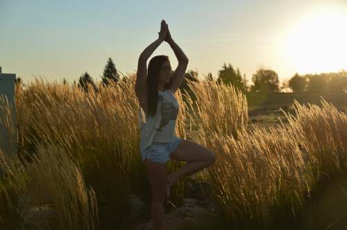 grass woman doing yoga pose outside near grass plant