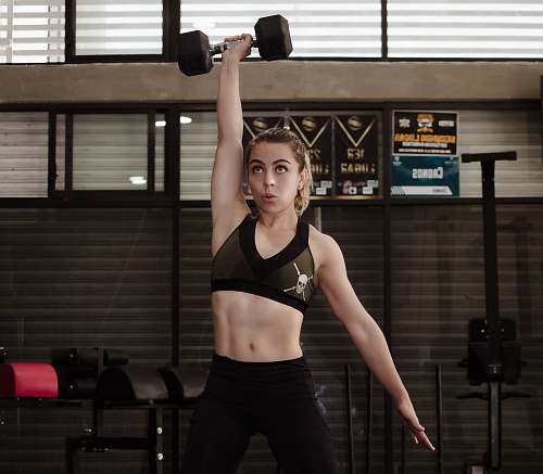 person woman exercising with dumbbell inside gym sport