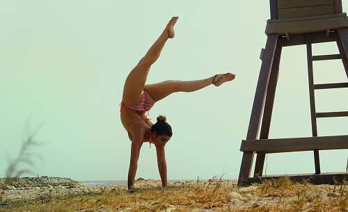 person woman in pink bikini doing hand stand acrobatic