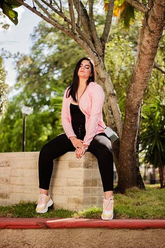 apparel woman in pink jacket sitting on concrete slab clothing