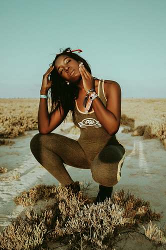person woman in sand touching her face clothing