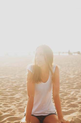 person woman in white blouse sitting on brown sand people