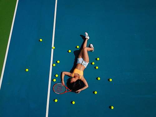 person woman in yellow crop top laying down on hard court sport