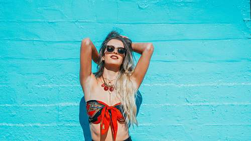 person woman leaning on teal wall while facing up people