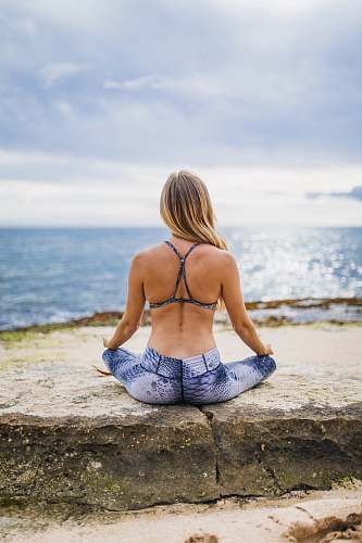person woman meditating front of sea at daytime back