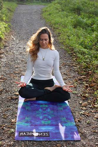 person woman meditating on dirt pathway with blue Yoga mat sleeve