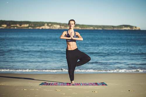person woman performing yoga on shore during daytime fitness