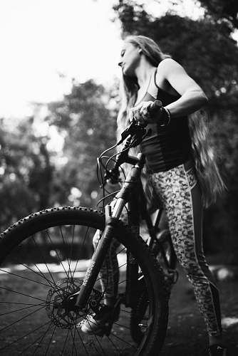 person woman riding bicycle near trees black-and-white