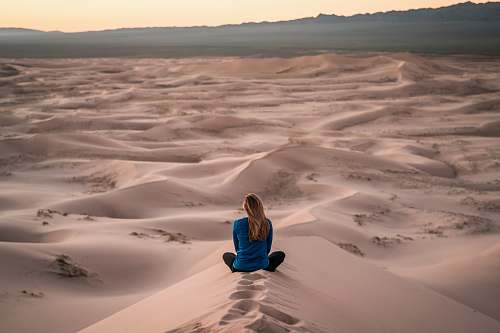 person woman sitting on sand field people