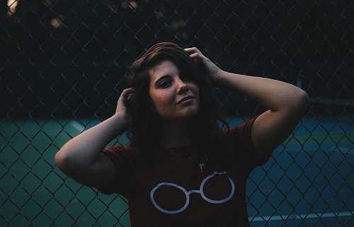 people woman standing in front of cyclone fence person