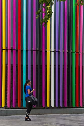 person woman standing near the multicolored building wall at daytime people
