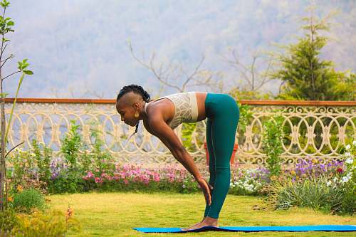 person woman wearing teal pants standing on yoga mat outdoors