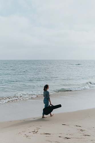 person woman with gig bag at beach outdoors