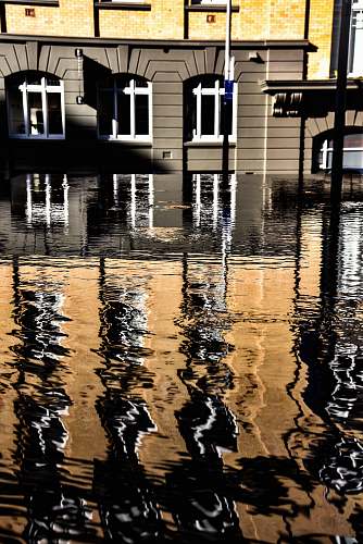 flood brown and yellow concrete building near body of water with self reflection water