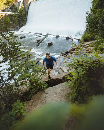 outdoors man climbing on cliff beside river river