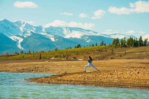 outdoors woman doing yoga near river mountain