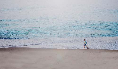 coast person running on seashore during daytime beach