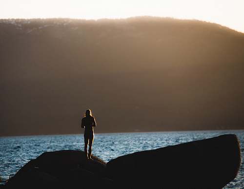 sea person standing on gray stone near body of water lake tahoe